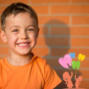 Little boy smiling in front of brick wall.