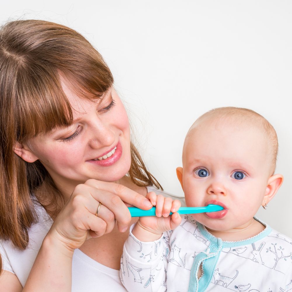 Mother brushing her babies new teeth.