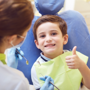 Young boy smiling with thumbs up in dental chair